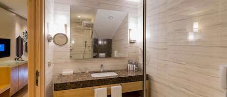 A modern bathroom with a granite countertop, a sink, a mirror, and a shower area.