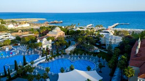 Un resort con varias piscinas, palmeras y vista al mar.
