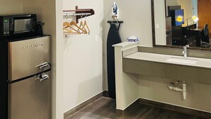 A modern bathroom with a built-in microwave, a vanity with a mirror, and a towel rack. - Americas Best Value Inn La Porte (La Porte)