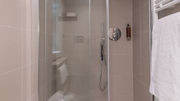 A modern shower enclosure with a glass door, a built-in bench, and a towel rack.