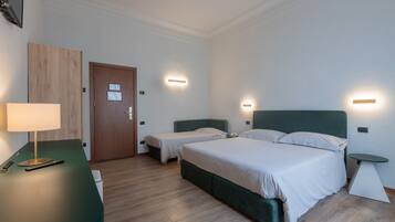 Une chambre d’hôtel avec deux lits, un bureau avec une lampe et des tables de chevet.