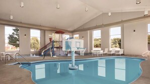 Une piscine intérieure dotée d’un plongeoir, d’un panier de basketball et de chaises longues.