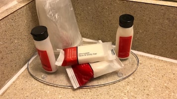 A bathroom counter with toiletries including a face and body bar, a lotion bottle, and a massage bar.