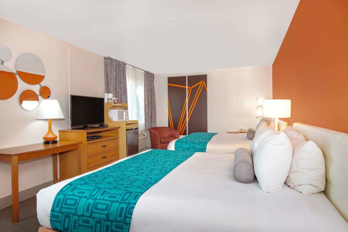 A hotel room with a bed, a desk, a television, and a chair.