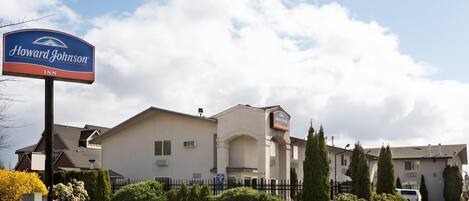 A Howard Johnson Inn with a signboard, a parking lot, and a building with a flat roof and multiple windows.