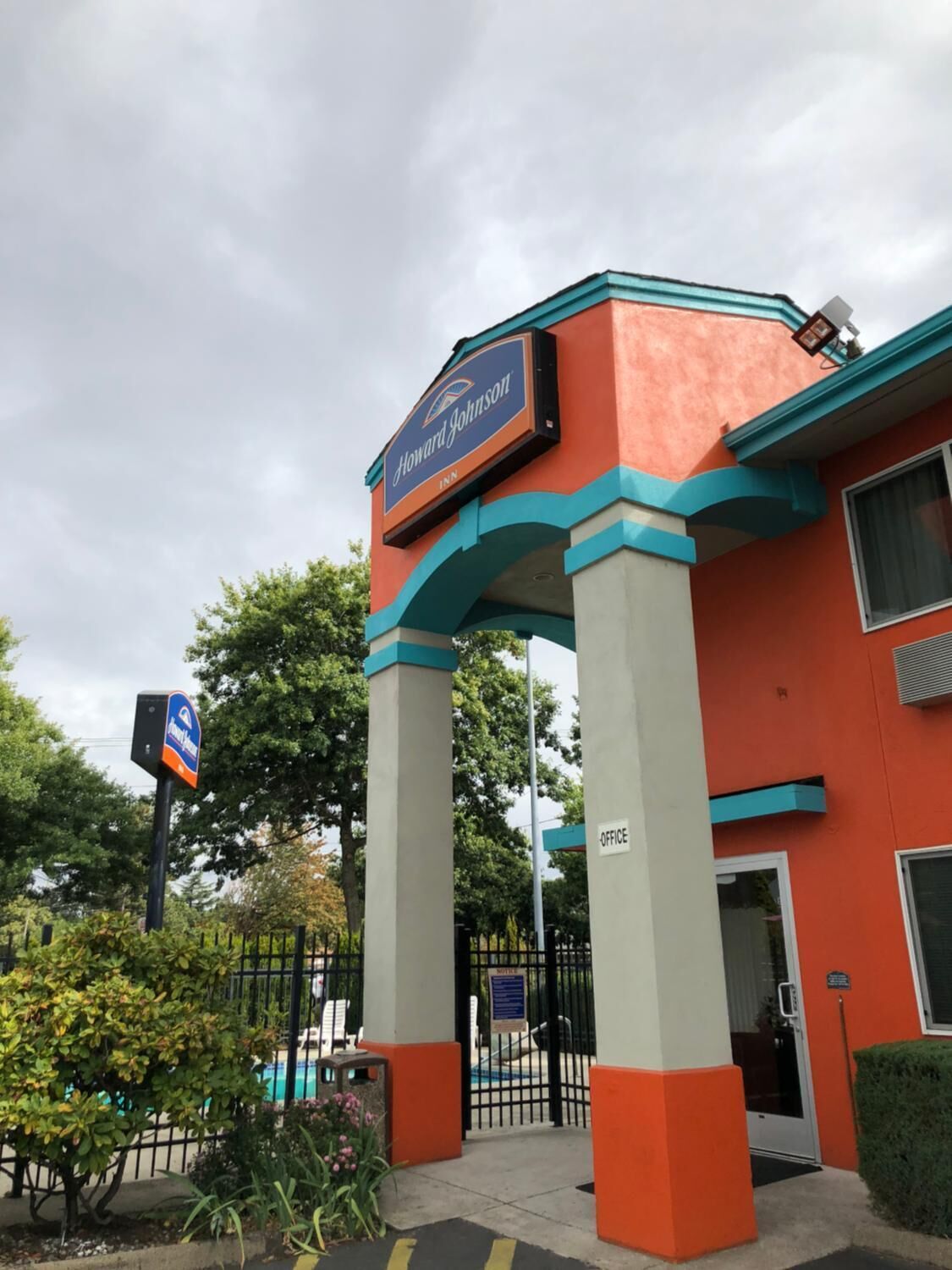 La entrada al hotel Howard Johnson, con un cartel sobre la entrada y un letrero que indica la ubicación de la oficina.