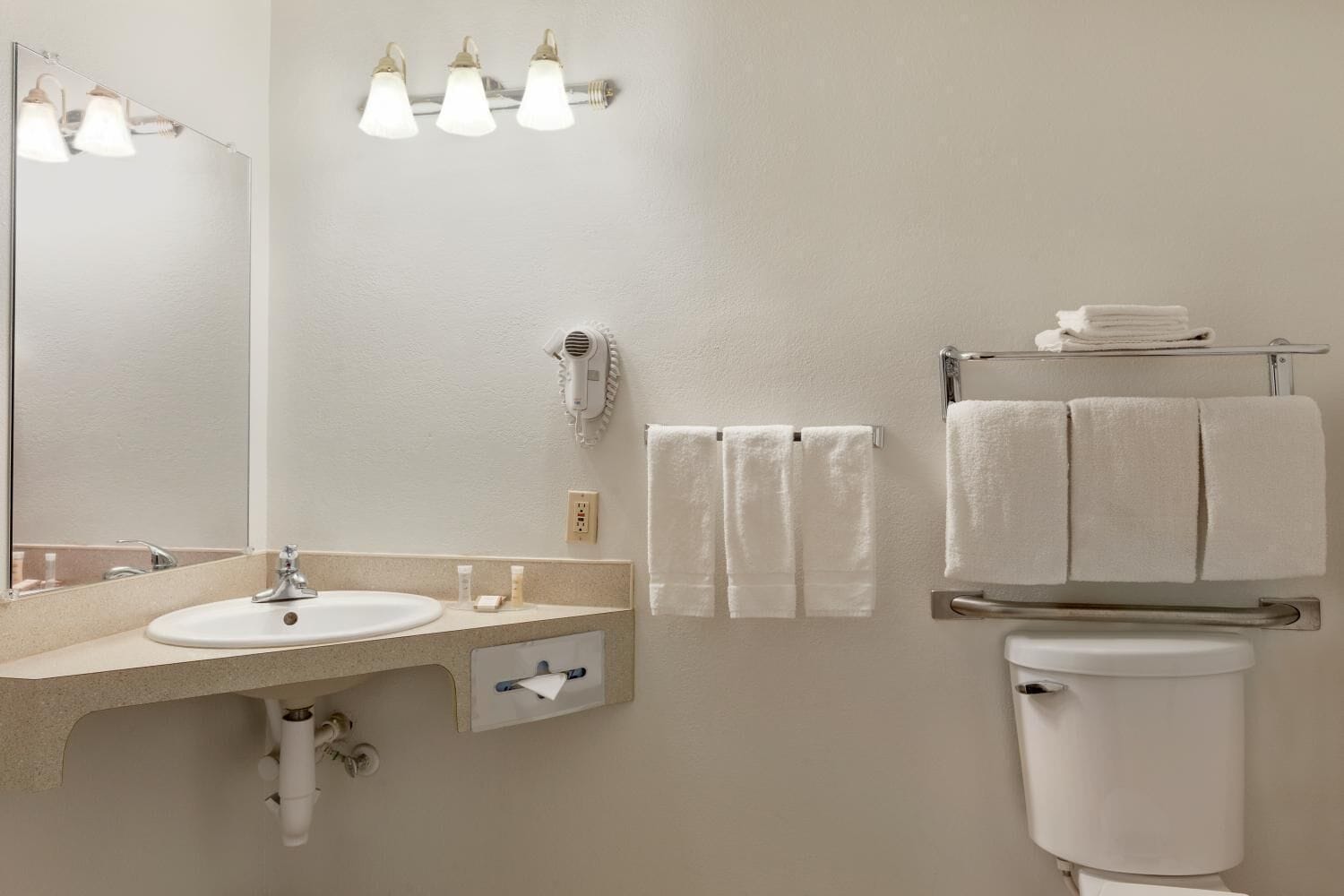 A bathroom with a sink, mirror, towel rack, and a toilet.