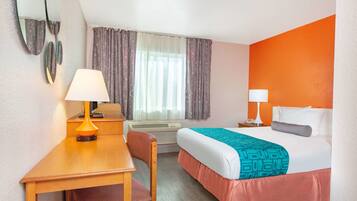 Una camera d'albergo con un letto, una scrivania, una sedia e due lampade da comodino.
