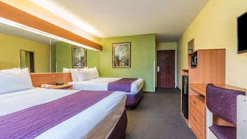 A hotel room with two beds, a desk, a chair, a mirror, and a door.