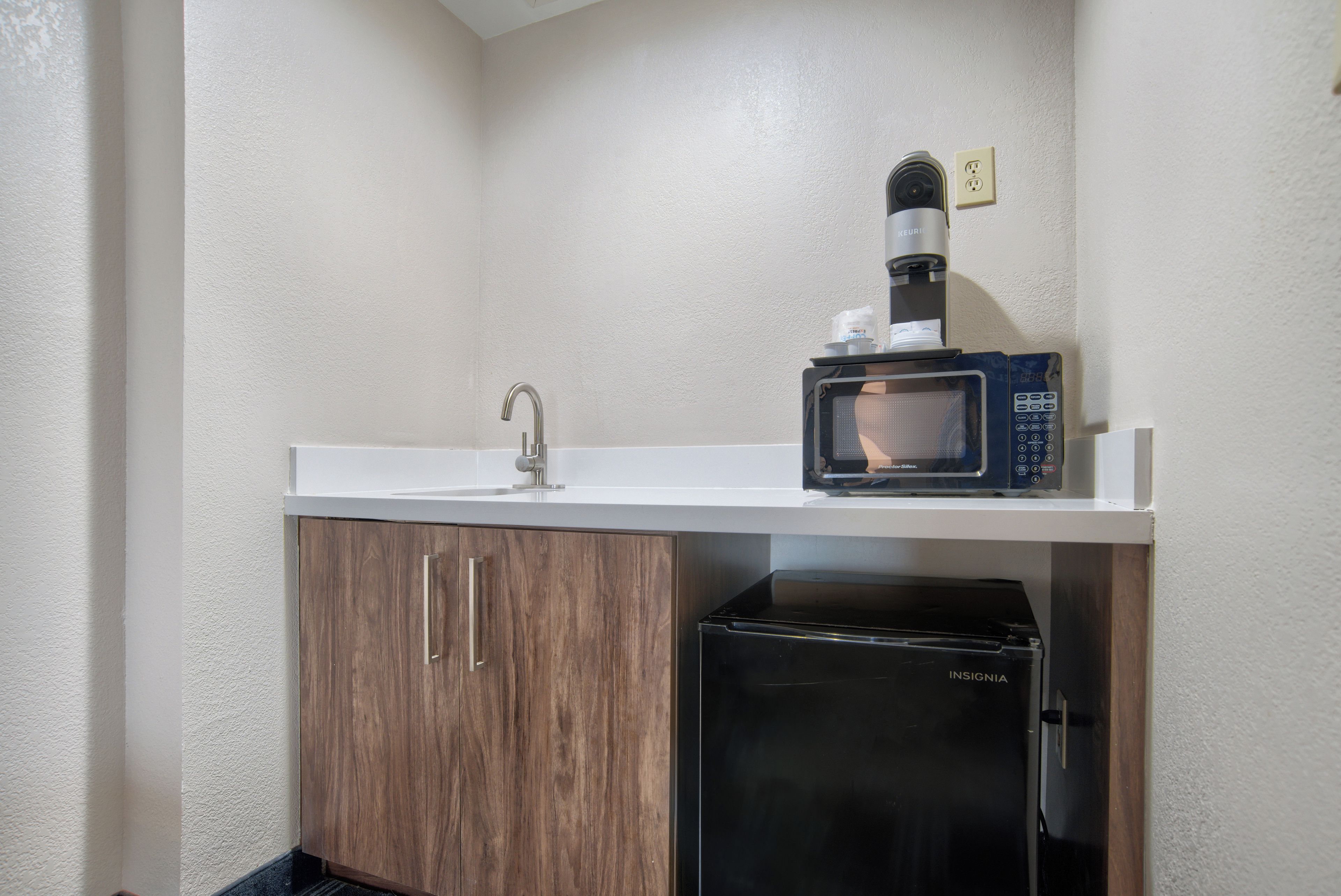 A compact kitchenette with a sink, a microwave, and a compact refrigerator.