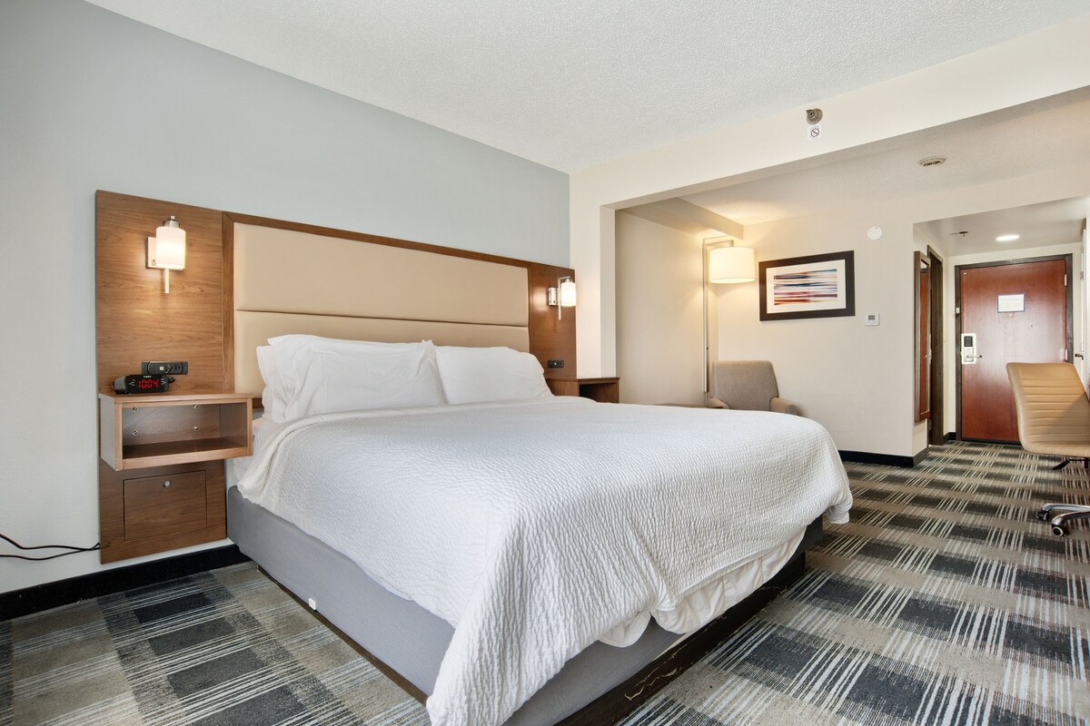 A hotel room with a large bed, bedside tables, a desk, and a chair.