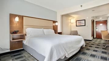 Une chambre d’hôtel avec un grand lit, des tables de chevet, un bureau et une chaise.