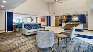 A spacious lobby with a reception desk, seating area, and a staircase leading to upper floors.
