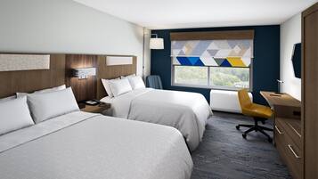 Hotelkamer met twee bedden, een bureau, een stoel, een raam met uitzicht en een lamp.