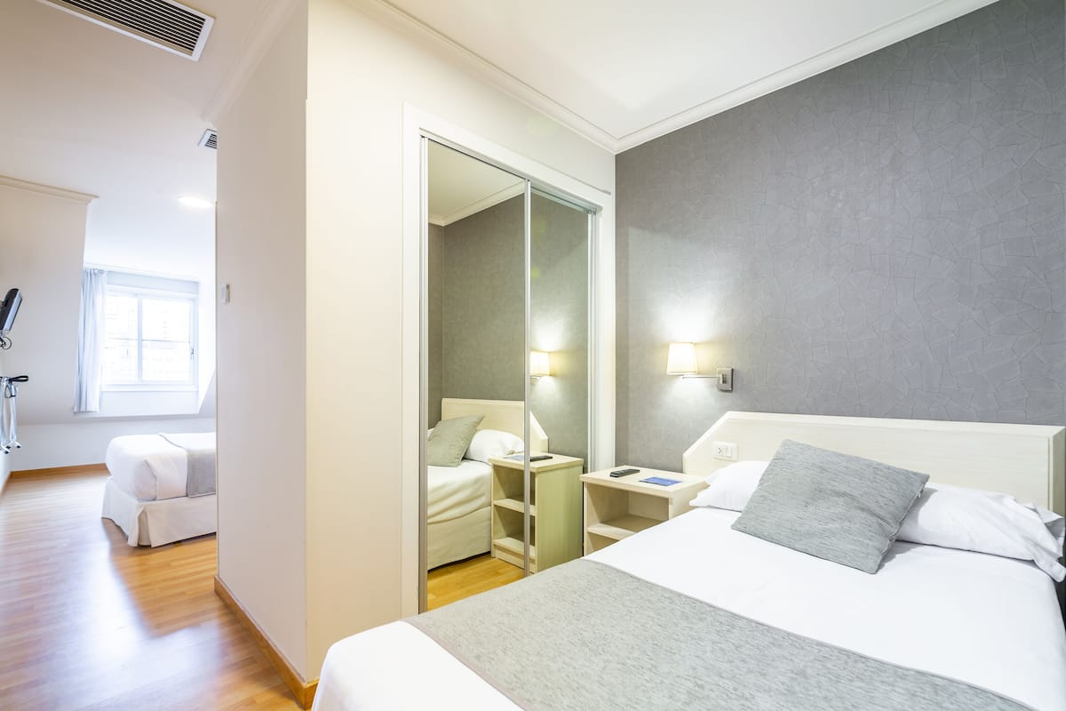 Ein Hotelzimmer mit einem großen Bett, einem Nachttisch, einem Schrank und einem Spiegel.