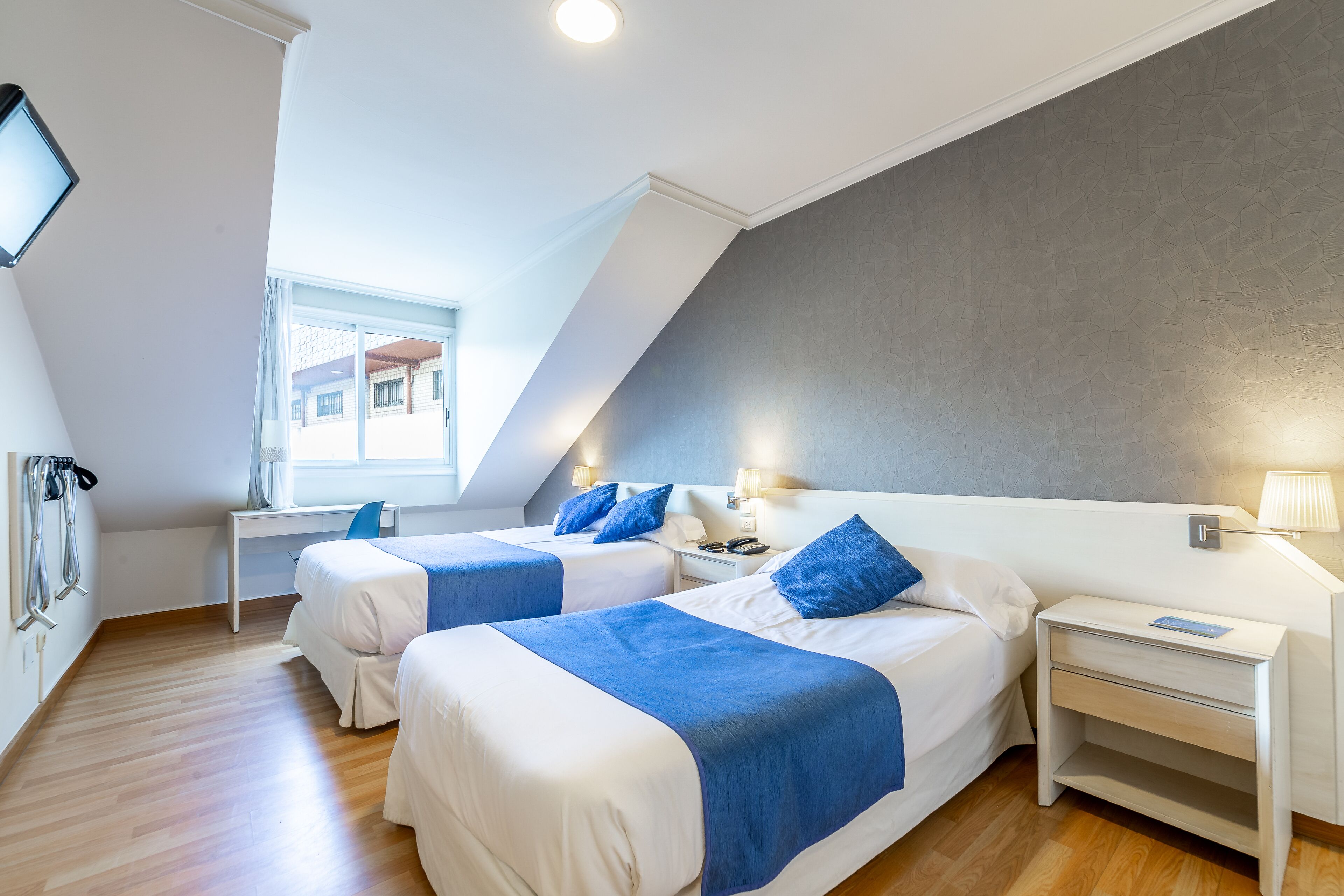 Une chambre d’hôtel moderne avec deux lits, un bureau et une fenêtre.