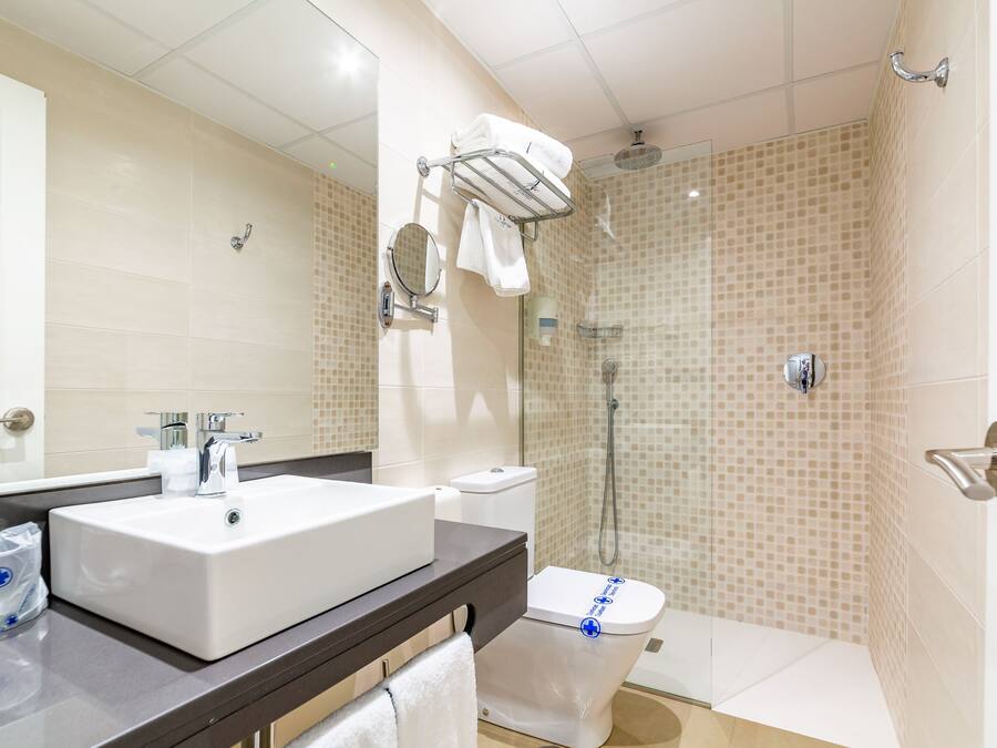 Un baño moderno con lavamanos blanco, inodoro y zona de ducha.