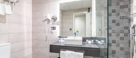 A modern bathroom with a glass shower enclosure, a white sink, and a mirror.