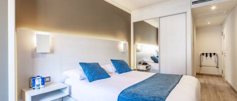 Una habitación de hotel con cama, mesita de noche y espejo.