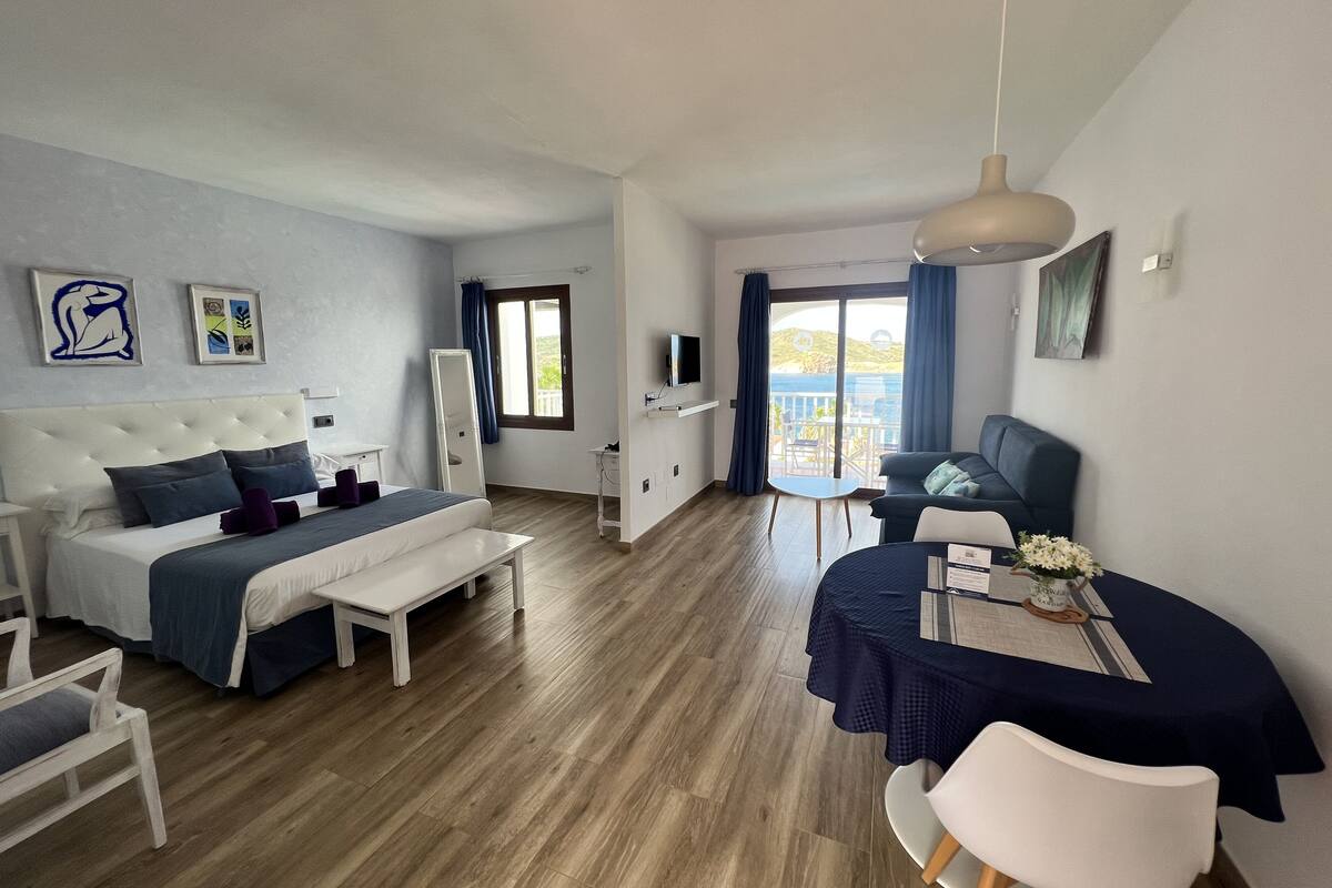Ett modernt hotellrum med en säng, ett skrivbord och en balkong med utsikt.