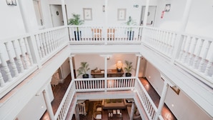 A multi-level interior with white railings, a central seating area with a table and chairs, and potted plants. - Hotel Palacio de Los Navas (Granada)