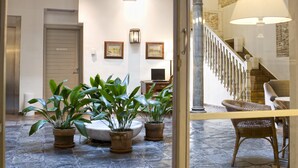 A lobby with a staircase, potted plants, and a reception desk. - Hotel Palacio de Los Navas (Granada)