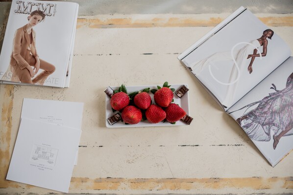 Una revista, una modelo, un plato de fresas y un menú sobre una mesa.