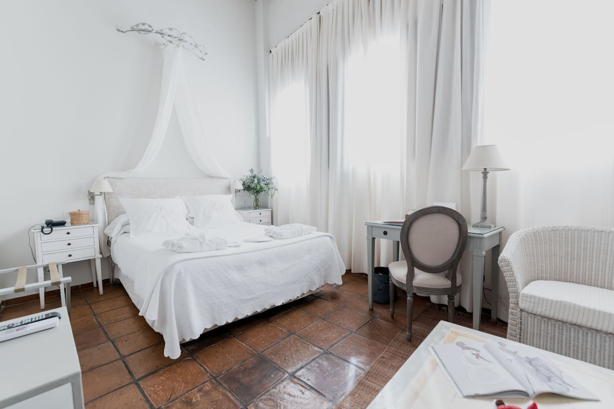 Habitación de hotel con cama, escritorio, silla y lámpara.