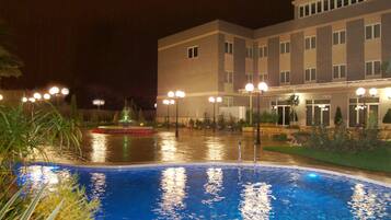 Een buitenzwembad, parasols bij het zwembad en ligstoelen