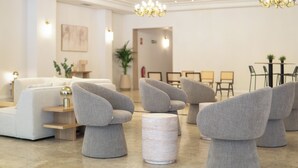 En moderne lobby med sofaer, stole, et rundt bord og en lysekrone.