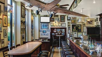 Un bar con mesas y sillas de madera, una barra con botellas y un techo con un gran modelo de avión.