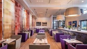 A modern restaurant interior with tables and chairs, a bar area, and artwork on the walls. -  IntercityHotel Frankfurt Airport Terminal 3 (Frankfurt)