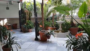 A courtyard with potted plants, a fountain, and tiled flooring. - Casa de los Azulejos (Córdoba)