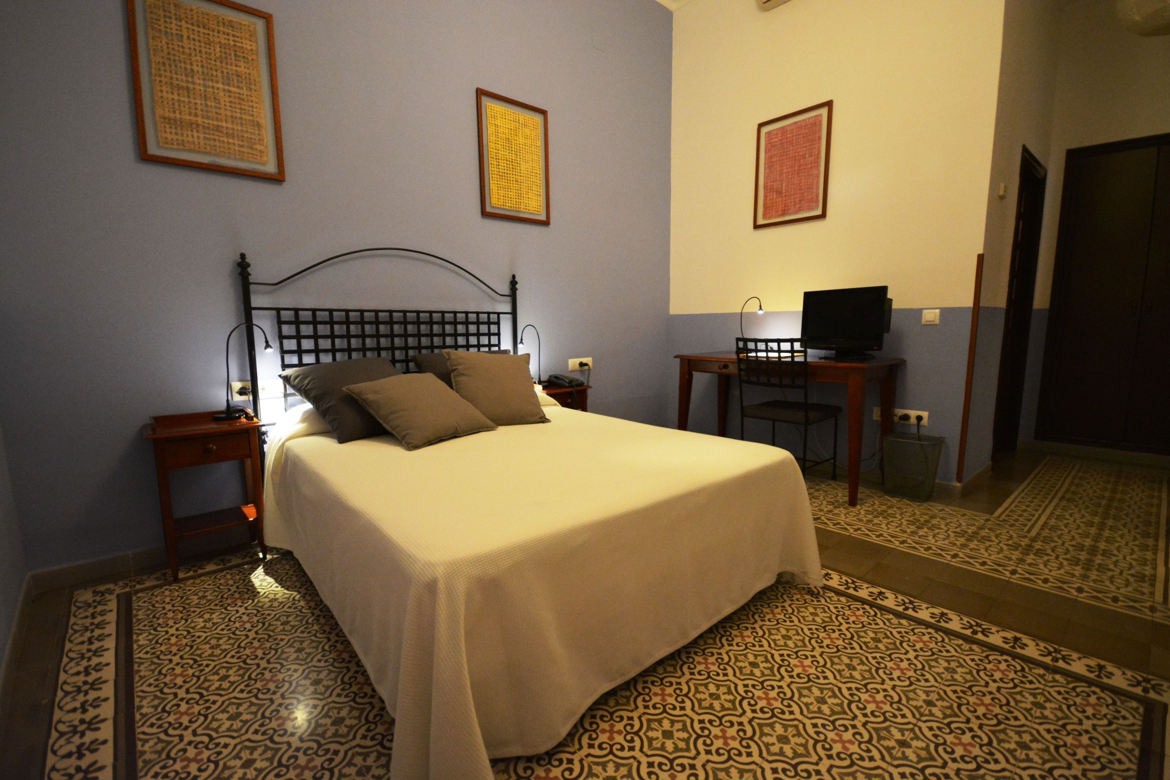 A neatly made bed with a headboard, a bedside table with a lamp, and a television on a small table beside the bed.