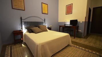 A neatly made bed with a headboard, a bedside table with a lamp, and a television on a small table beside the bed.