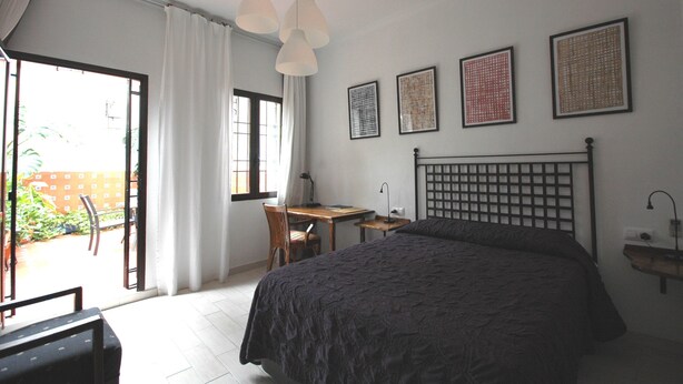 A bedroom with a bed, a desk, and a chair. There are three framed pictures on the wall. - Casa de los Azulejos (Córdoba)