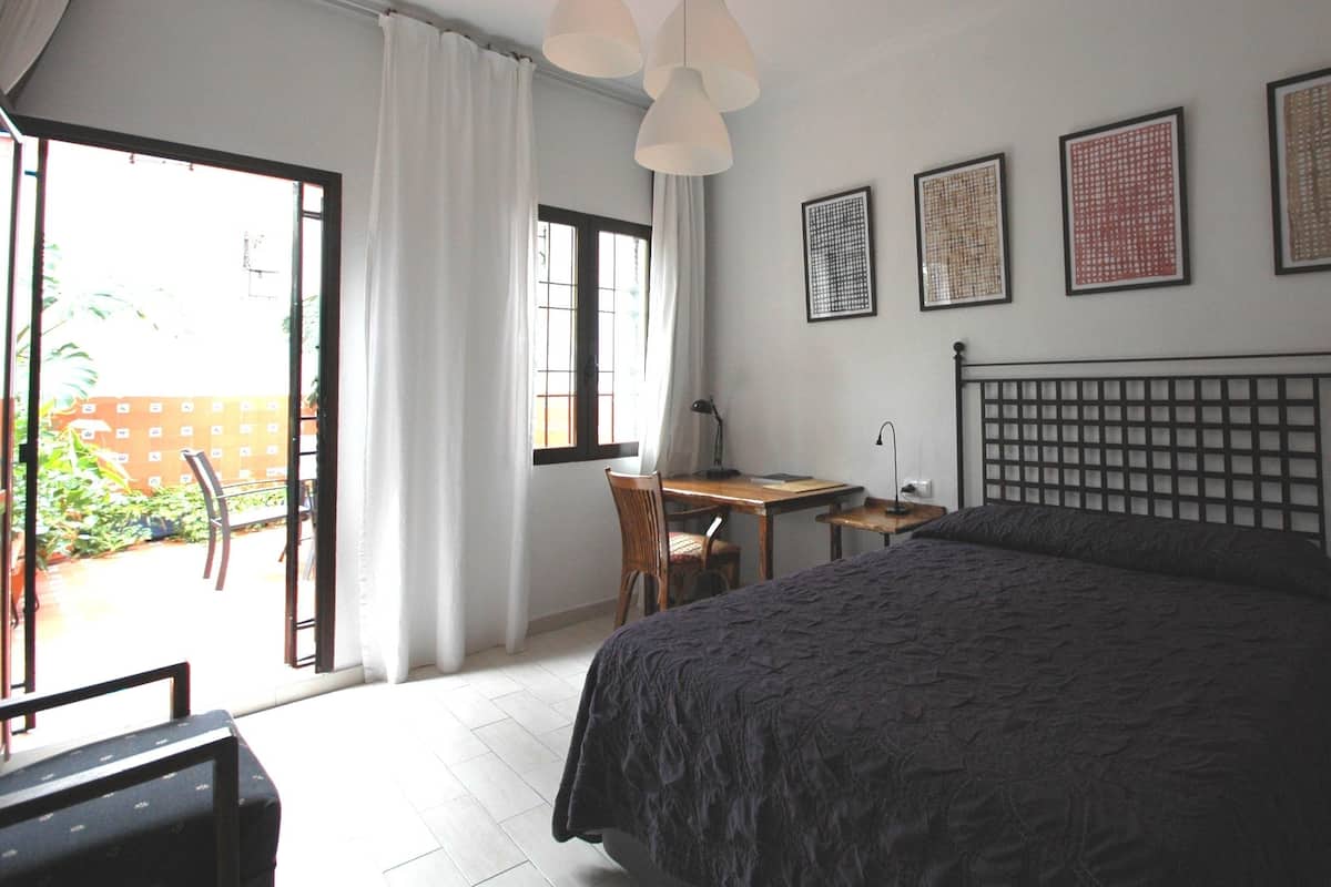 A bedroom with a bed, a desk, and a chair. There are three framed pictures on the wall.