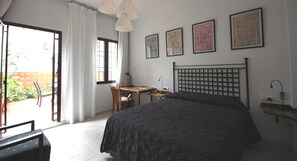 Une chambre à coucher avec un lit, un bureau et une chaise. Il y a trois tableaux encadrés accrochés au mur.