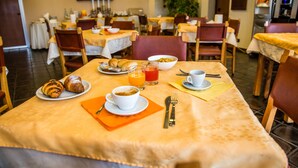 A dining area with tables set for breakfast, including croissants, coffee, and orange juice. - Hotel Galant (Venaria Reale)