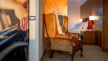 Ein Hotelzimmer mit einem großen Bett, einem Nachttisch, einer Lampe und einem Ledersessel.