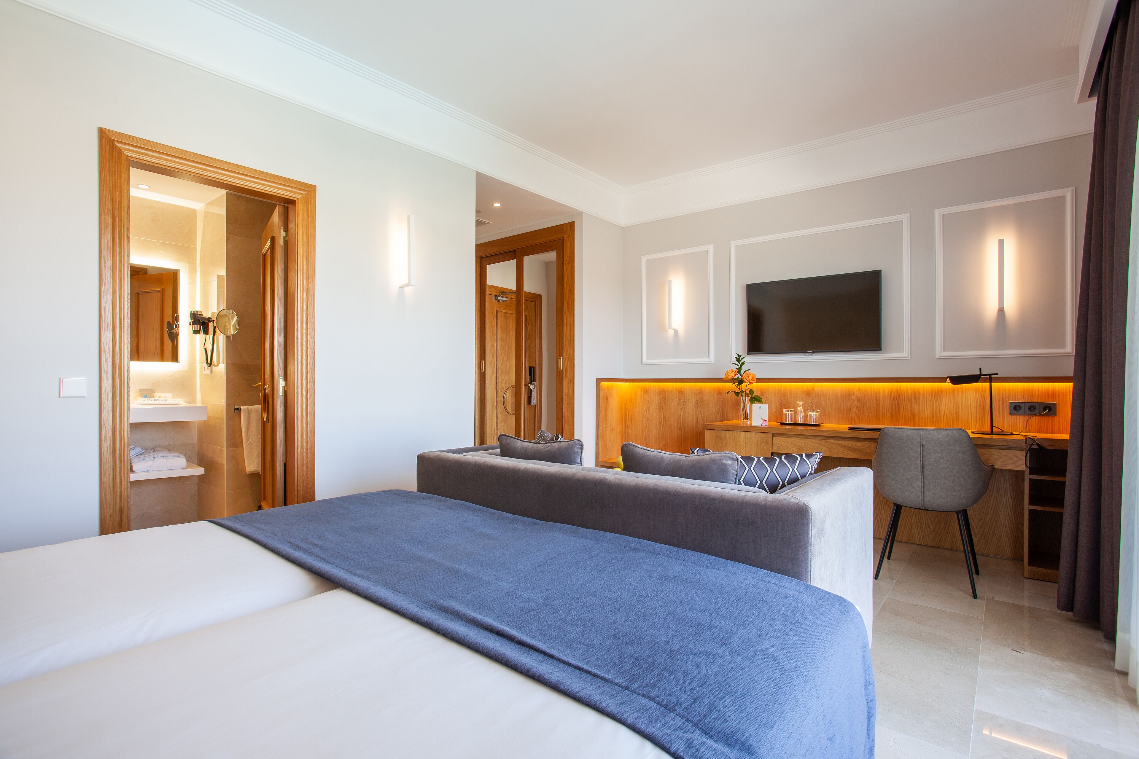 Una habitación de hotel con una cama grande, un sofá, un escritorio y un televisor.