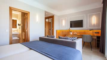 Habitació d'hotel amb un llit gran, un sofà, una taula de treball i una televisió.