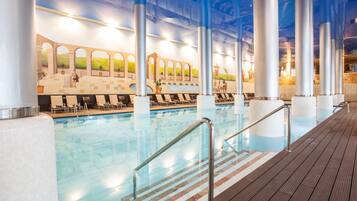 A swimming pool with a wooden deck, metal railings, and a mural on the wall.