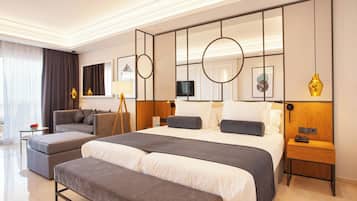 Una habitación de hotel moderna con una cama grande, un sofá, un banco, una mesita de noche y un televisor.