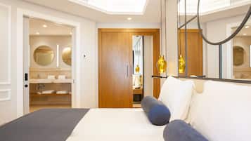 A modern bedroom with a large bed, a wooden wardrobe, and a bathroom visible through an open door.