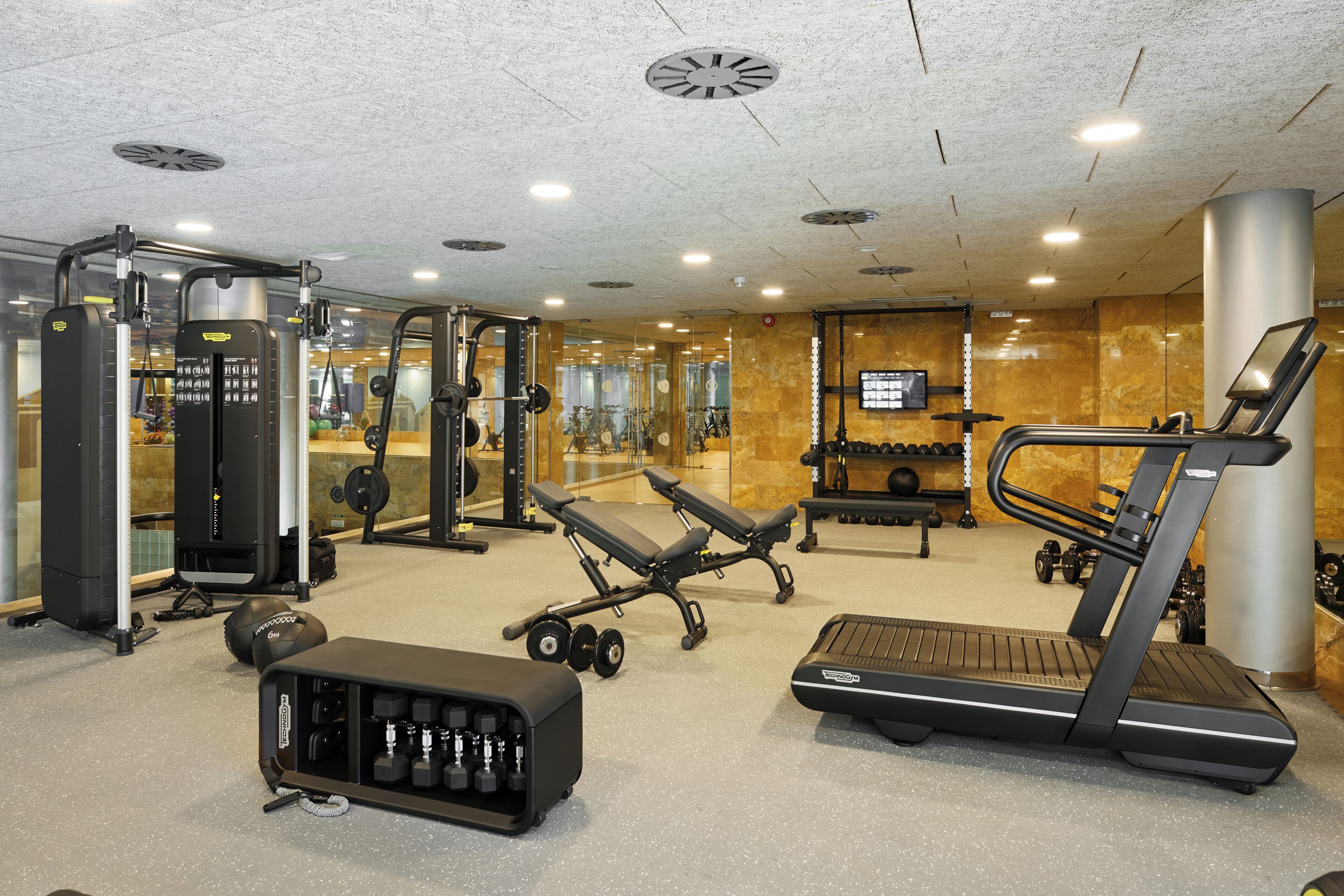 Un gimnasio con equipo de ejercicio, una banca, una cinta de correr y un espejo.