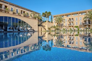 Ein Hotel mit Pool, Palmen und blauem Himmel.