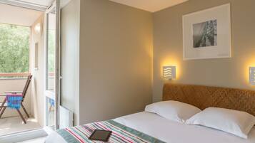 A hotel room with a bed, a window, a balcony, and a wall-mounted picture.