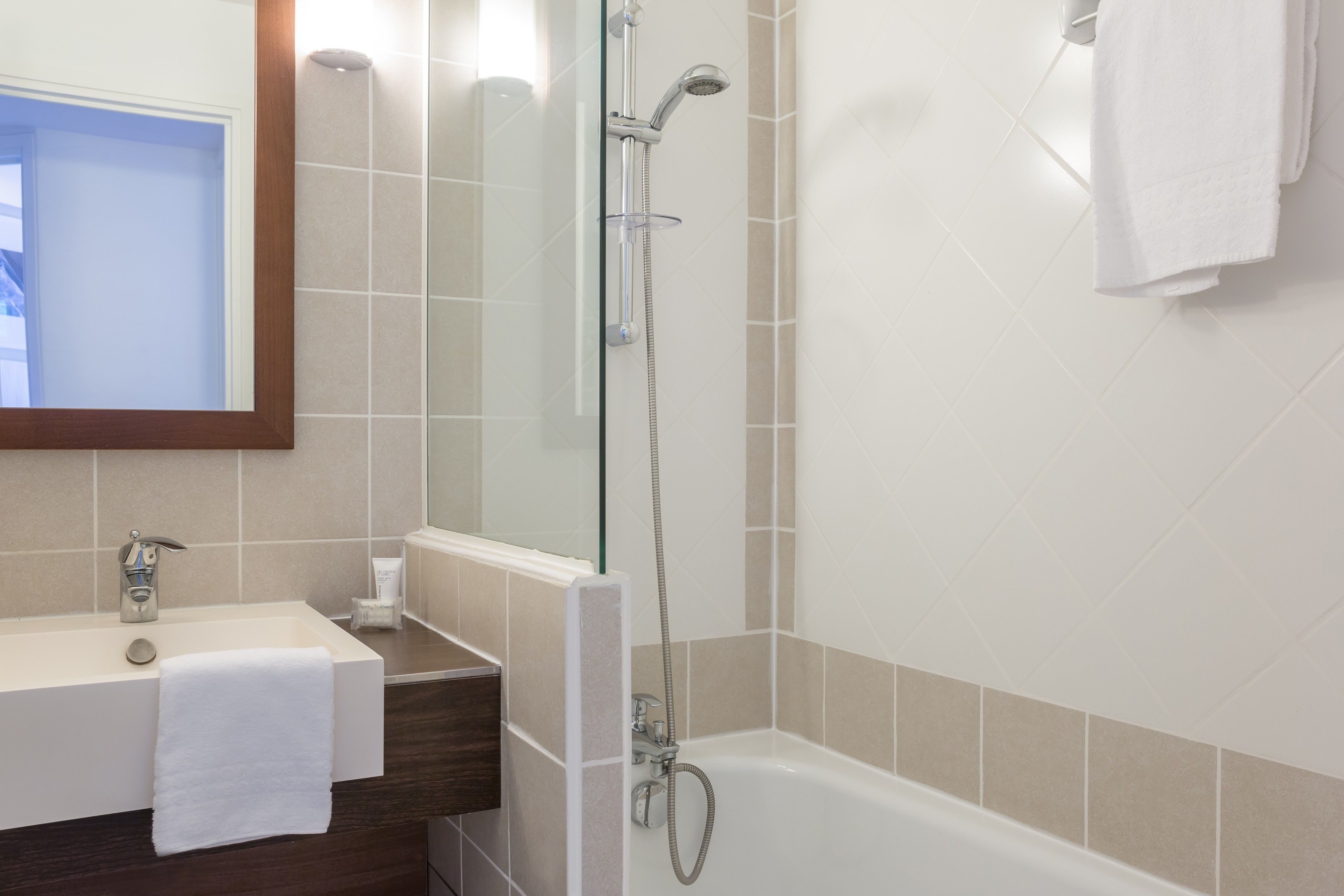 A bathroom with a sink, mirror, and shower.