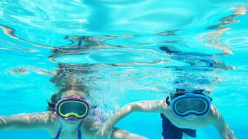 Une vue sous-marine d’une piscine où l’on aperçoit deux personnes portant des lunettes de natation.